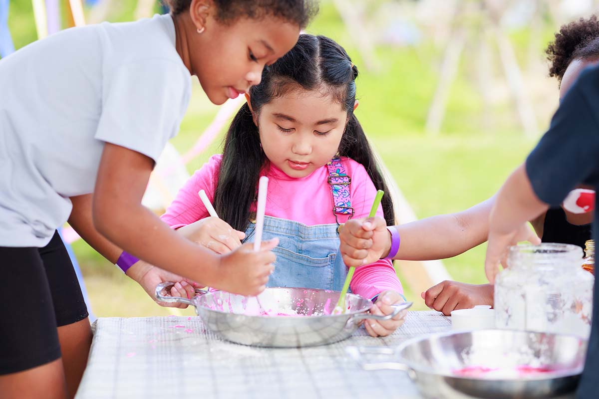 Children take part in a craft activity in a park.