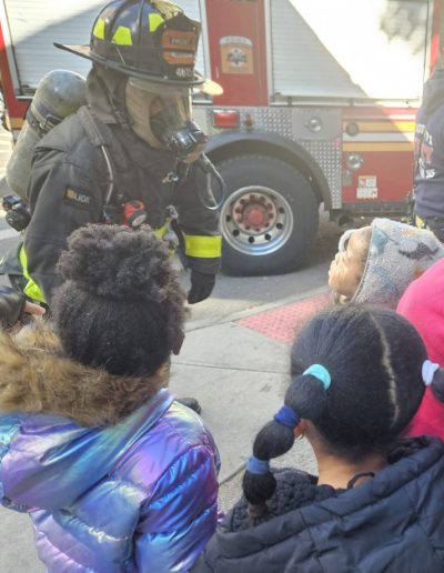 A NYC firefighter shows firefighting gear to during a visit to Luminous.