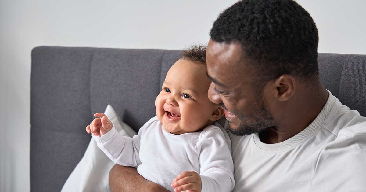 A man cuddles a happy baby.