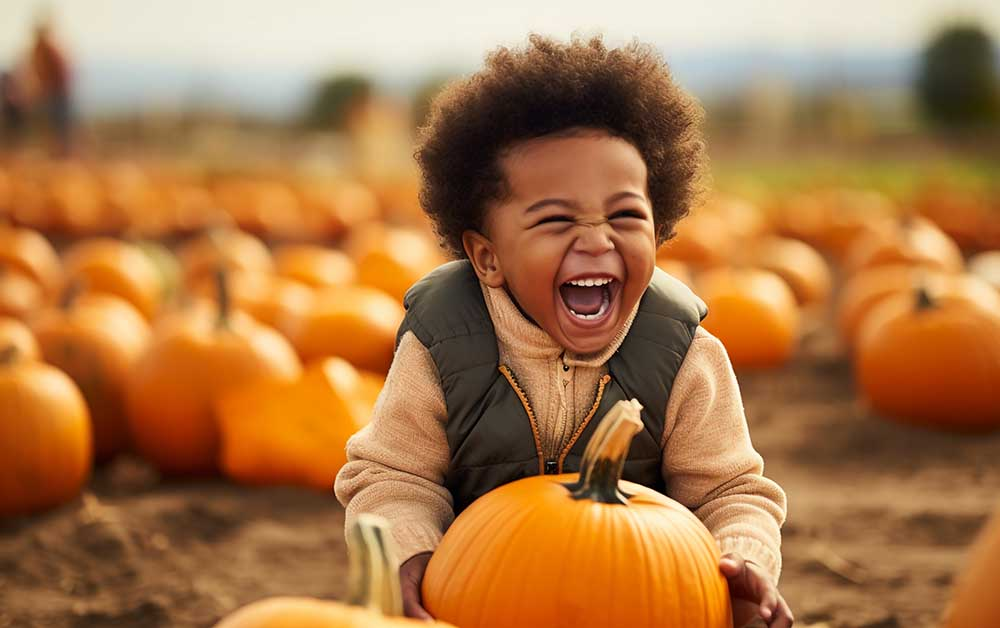 Happy little African American boy in a pumpkin patch in autumn,